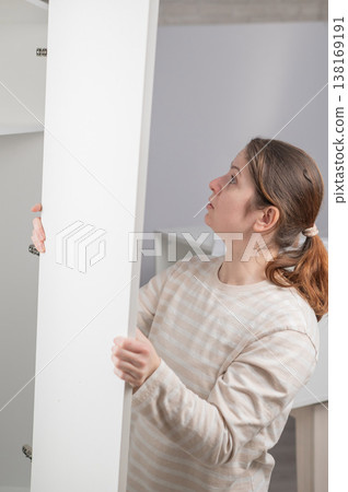 A Caucasian woman assembles a wardrobe. A Caucasian woman assembles a wardrobe. 138169191