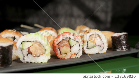 Sushi rolls are arranged on a black plate in a restaurant setting during the evening meal time Sushi rolls are arranged on a black plate in a restaurant setting during the evening meal time 138169820