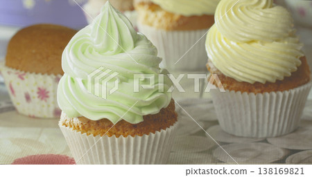 Cupcakes with colorful frosting are placed on a table in a bright setting during a casual gathering Cupcakes with colorful frosting are placed on a table in a bright setting during a casual gathering 138169821