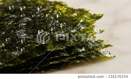 Stacked dark nori sheets with morning dew droplets on marble background 138170154