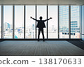 A businessman with his arms outstretched, facing outwards from the building. 138170633