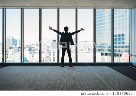 A businessman with his arms outstretched, facing outwards from the building. A businessman with his arms outstretched, facing outwards from the building. 138170633
