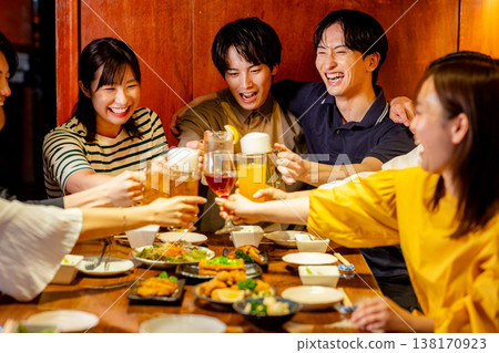 一對年輕男女在居酒屋(日本酒吧)碰杯。 一對年輕男女在居酒屋(日本酒吧)碰杯。 138170923