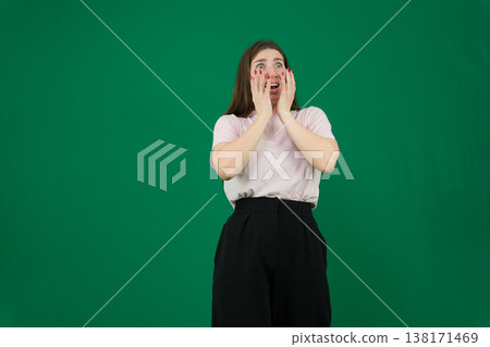 Young woman with surprised expression wearing a geometric sweater against a purple background showcasing fashion style and playful energy 138171469