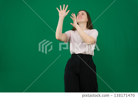 different emotions of a young girl on a green background chromakey beautiful facial features real people pink T-shirt white skinned European. black flared wide leg trousers 138171470