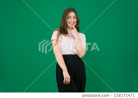 Happy confident woman different emotions of a young girl on a green background chromakey beautiful facial features real people pink T-shirt white skinned European. black flared wide leg trousers 138171471