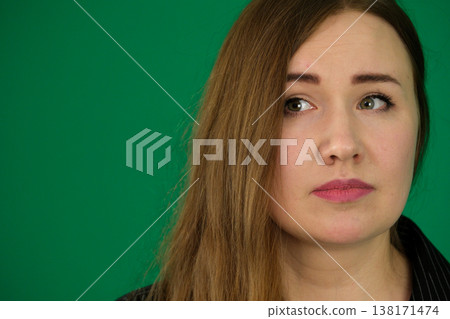 Woman volunteer in shirt with thoughtful expression against isolated green background wall reflects contemplation and purpose. 138171474