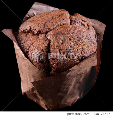 Delicious chocolate muffin in brown paper tulip liner on black background side view extreme close up sweet bakery dessert snack for menu Delicious chocolate muffin in brown paper tulip liner on black background side view extreme close up sweet bakery dessert snack for menu 138171546