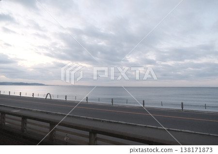 陰雲密佈的大海和道路;背景是寧靜而略顯模糊的海邊景色。 陰雲密佈的大海和道路;背景是寧靜而略顯模糊的海邊景色。 138171873