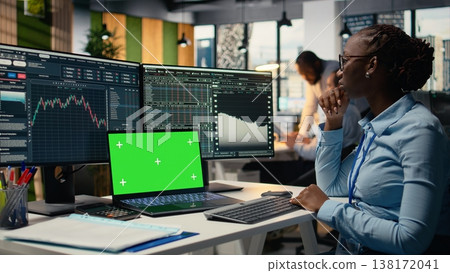 Financial analyst at work doing research on stock market shares using green screen laptop. African american worker in office reading reports on mockup notebook to make trading decisions Financial analyst at work doing research on stock market shares using green screen laptop. African american worker in office reading reports on mockup notebook to make trading decisions 138172041