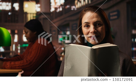 Mature person enjoying lecture at a public library and reading many books, feeling relaxed and increasing his knowledge during retirement period. Happy pensioner with spectacles. 138172091
