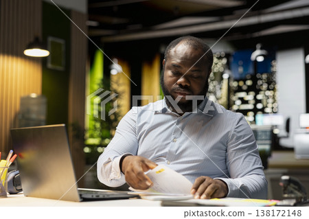African american strategist ripping a paper after writing the wrong idea, restarting his work in rage and crumpling the page sheet. Discontent man does a typo mistake while transcribing. 138172148