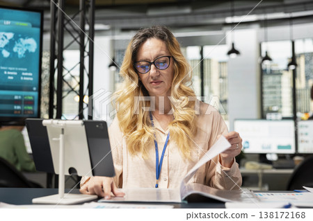 Chief executive officer evaluating productivity reports in business workspace, ensuring a synergy between performance metrics and enterprise objectives. Corporate feminism empowerment. Chief executive officer evaluating productivity reports in business workspace, ensuring a synergy between performance metrics and enterprise objectives. Corporate feminism empowerment. 138172168