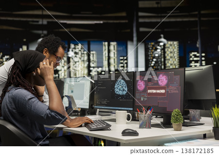 Young female programmer in office requests help from manager detecting and blocking hacker intrusion. Intern assisted by team leader coordinating incident response for network attack Young female programmer in office requests help from manager detecting and blocking hacker intrusion. Intern assisted by team leader coordinating incident response for network attack 138172185