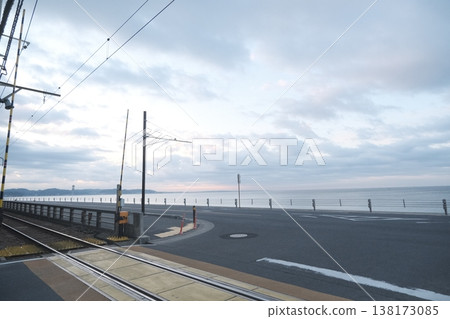 A railway crossing and road along the coast; a quiet coastal landscape and a cloudy sky. A railway crossing and road along the coast; a quiet coastal landscape and a cloudy sky. 138173085