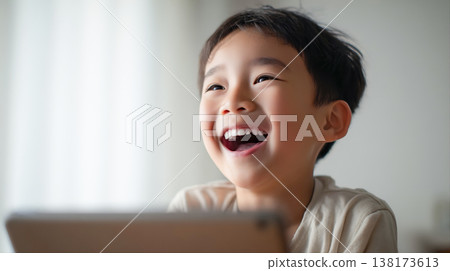 一個男孩看著筆記型電腦螢幕，歇斯底里地大笑。 138173613