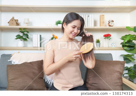 Woman brushing her hair on a couch at home 138174313