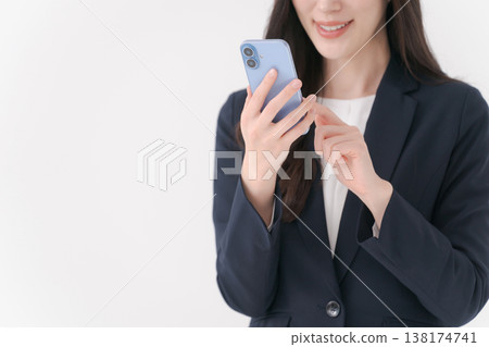 一位身穿西裝的女士面帶微笑,手裡拿著智慧型手機。 一位身穿西裝的女士面帶微笑,手裡拿著智慧型手機。 138174741