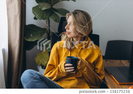 Freelance woman holding coffee thinking about projects in home office with focused mindset and calm remote work lifestyle Freelance woman holding coffee thinking about projects in home office with focused mindset and calm remote work lifestyle 138175238