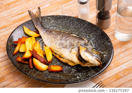 Baked dorada fish with vegetable garnish of fried potatoes 138175397