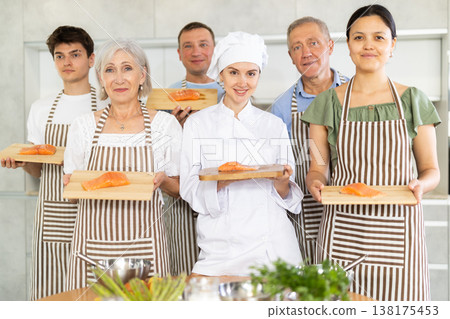 Smiling female chef posing along with cooking course participants 138175453