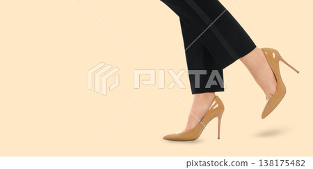 A woman steps forward in elegant high heels and pants A woman steps forward in elegant high heels and pants 138175482
