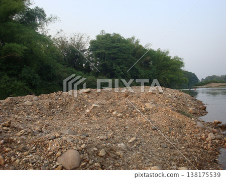Gravel riverbank river stone sand nature outdoor landscape forest green water Gravel riverbank with stone and sand beside calm river, lush green forest vegetation riverside soft sky creating Gravel riverbank river stone sand nature outdoor landscape forest green water Gravel riverbank with stone and sand beside calm river, lush green forest vegetation riverside soft sky creating 138175539