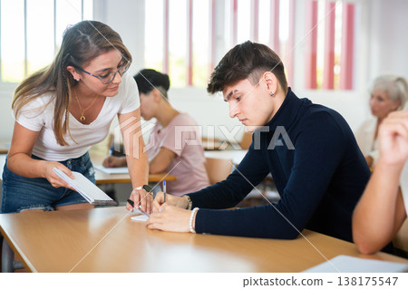 Female teacher prompts an adult student to solve equation Female teacher prompts an adult student to solve equation 138175547