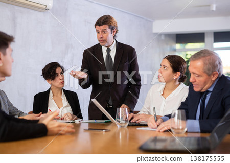 Furious male boss yelling at office colleagues of different ages taking notes at table with laptops 138175555