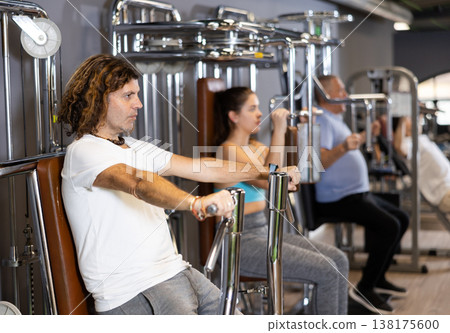 Sporty man doing chest press on execise machine in gym Sporty man doing chest press on execise machine in gym 138175600