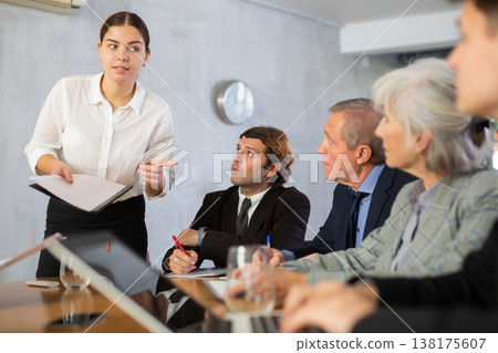 Young woman discussing business project with team in office Young woman discussing business project with team in office 138175607