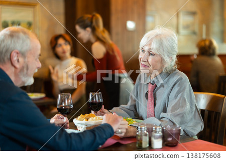 Elderly couple eating and talking in restaurant Elderly couple eating and talking in restaurant 138175608