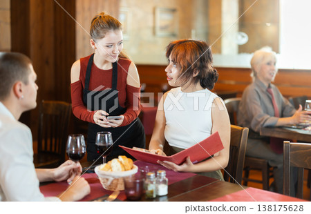 Young waitress bringing food to young couple in restaurant 138175628