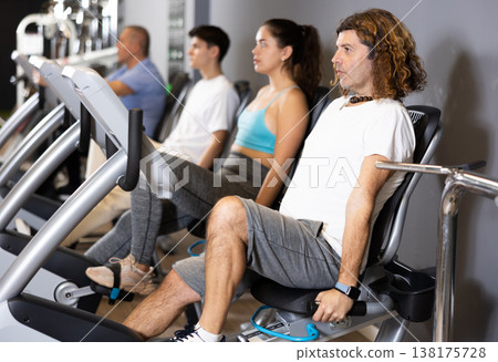 Motivated man doing cardio workout on exercise bike in gym Motivated man doing cardio workout on exercise bike in gym 138175728