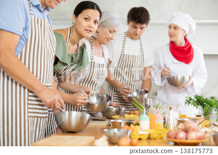 Cooking class - happy friends cooking and talking in kitchen Cooking class - happy friends cooking and talking in kitchen 138175773