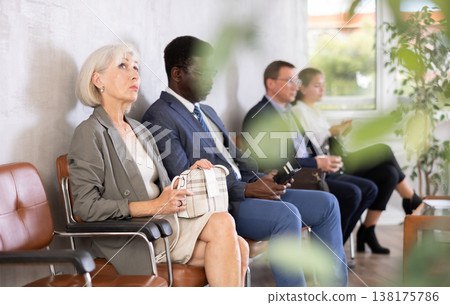 Serious-minded mature female candidate siting on chair and waiting for job interview in hallway 138175786