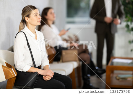 Adult woman sitting in job interview queue in office Adult woman sitting in job interview queue in office 138175798