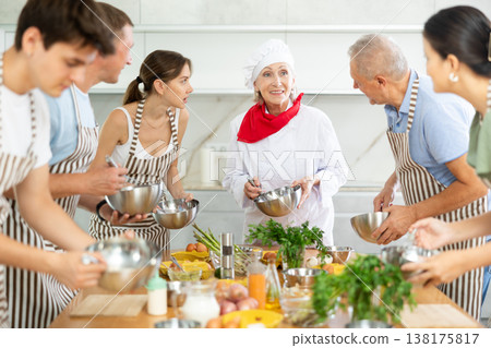 Amiable senior female chef running group culinary courses Amiable senior female chef running group culinary courses 138175817