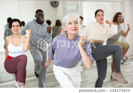 Mature woman rehearsing modern dance with group in dance school 138175833