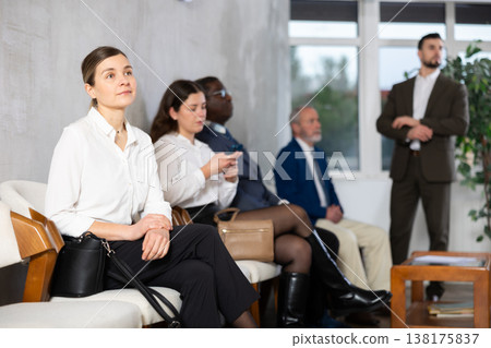 Applicants are waiting for interview, there is queue of people sitting in waiting room. 138175837