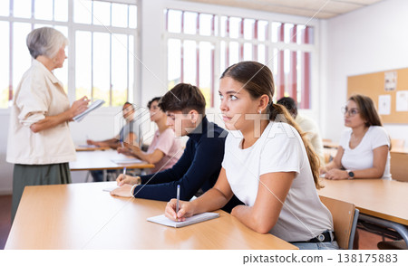 Interested girl listening and taking notes of lecture in university Interested girl listening and taking notes of lecture in university 138175883