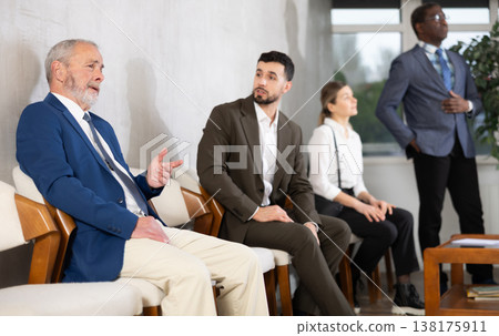 Young and elderly men talking while waiting in job interview queue 138175911