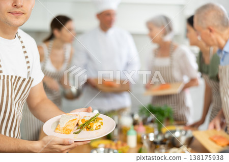 Happy young man attendee of culinary classes demonstrating meal made of salmon 138175938