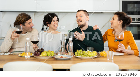 Two married couples are sitting at table, enjoying food and wine, chatting, talking, laughing. 138175940