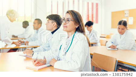 Doctors different age sitting at desk in classroom working during lesson at education class Doctors different age sitting at desk in classroom working during lesson at education class 138175942