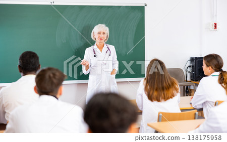Female doctor explaining new theme to adult students during class in university 138175958