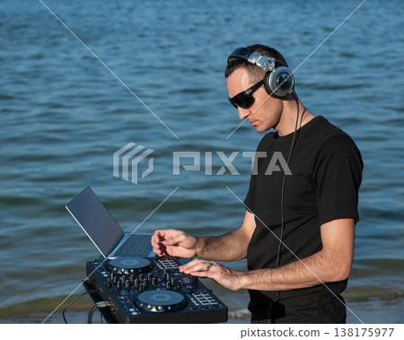 Caucasian man works as a DJ on the beach. Caucasian man works as a DJ on the beach. 138175977