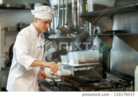 Young male cook preparing dish in restaurant kitchen 138176035