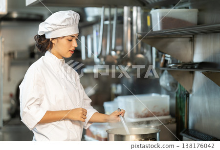 Young female cook preparing dish in restaurant kitchen 138176042