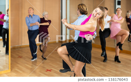 Middle-aged pair practicing Latino dance in dance studio Middle-aged pair practicing Latino dance in dance studio 138176043